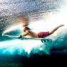 Young surfer dives under the ocean wave with surf board and pe / Sport