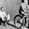 Woman on a bicycle pulling a grown man on a toy tricycle / Vintage